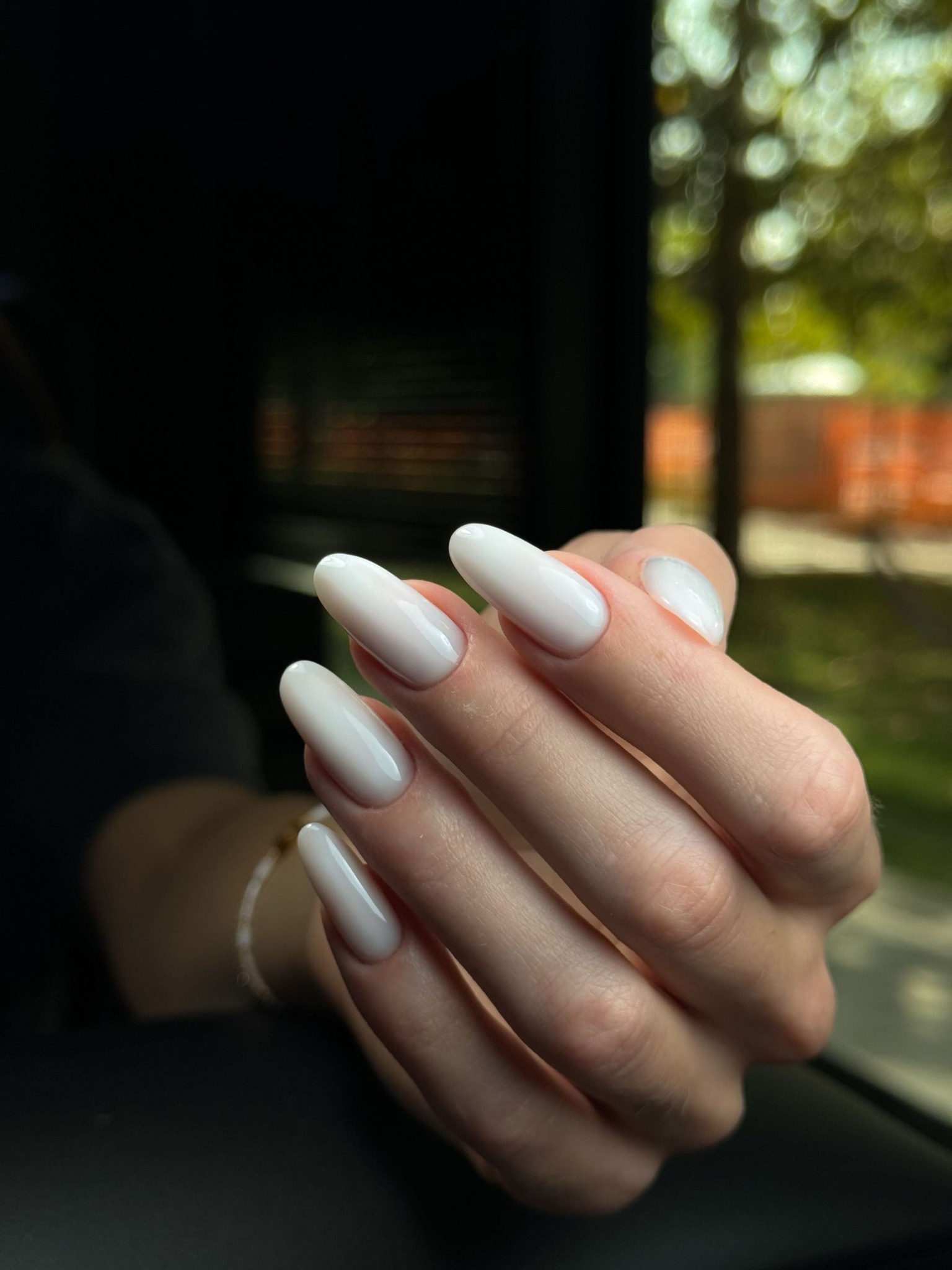 Mleczny biały manicure na paznokciach o kształcie migdała, w zbliżeniu.