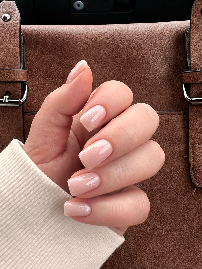 Jasny nude manicure z subtelnym połyskiem na paznokciach o miękkim kwadratowym kształcie.